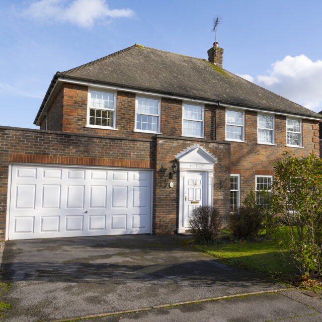 Front view of a brick house with a white garage and front door.