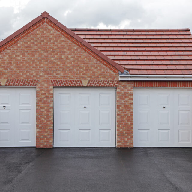 Three white garages in a red brick property.